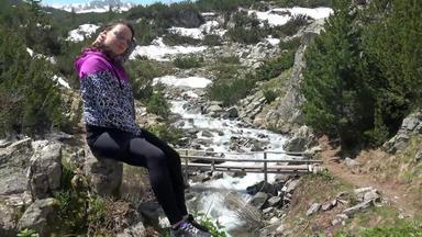 女孩需要休息徒步旅行坐着岩石<strong>享受</strong>山春天雪融化水域流动呃稳定摄像头股票镜头